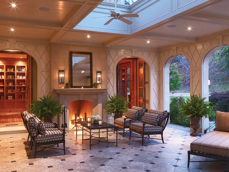 The screened porch includes a fireplace, a signature feature of the architect’s designs.