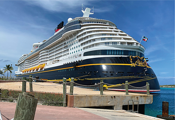 Disney Wish, docked at Castaway Cay, while families play.